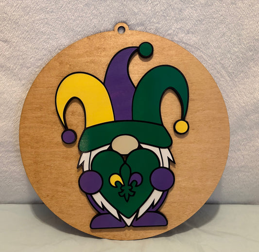 Wooden sign with a colorful jester hat and heart design on a plain background