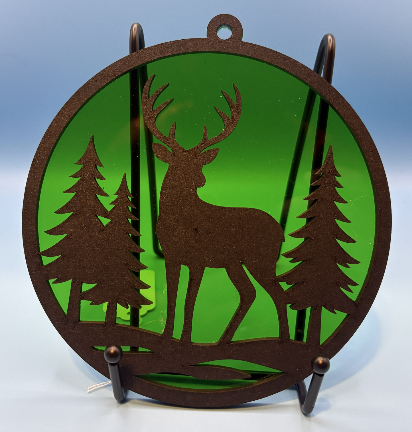 Decorative metal wall art with a deer and forest design on a green background