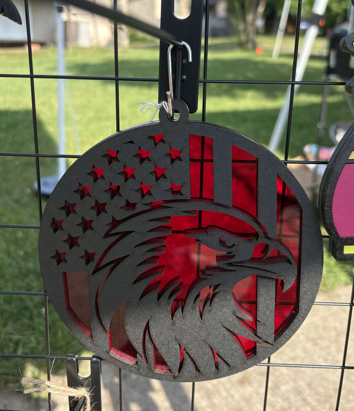 Decorative metal ornament with American flag and eagle design on a wire rack.