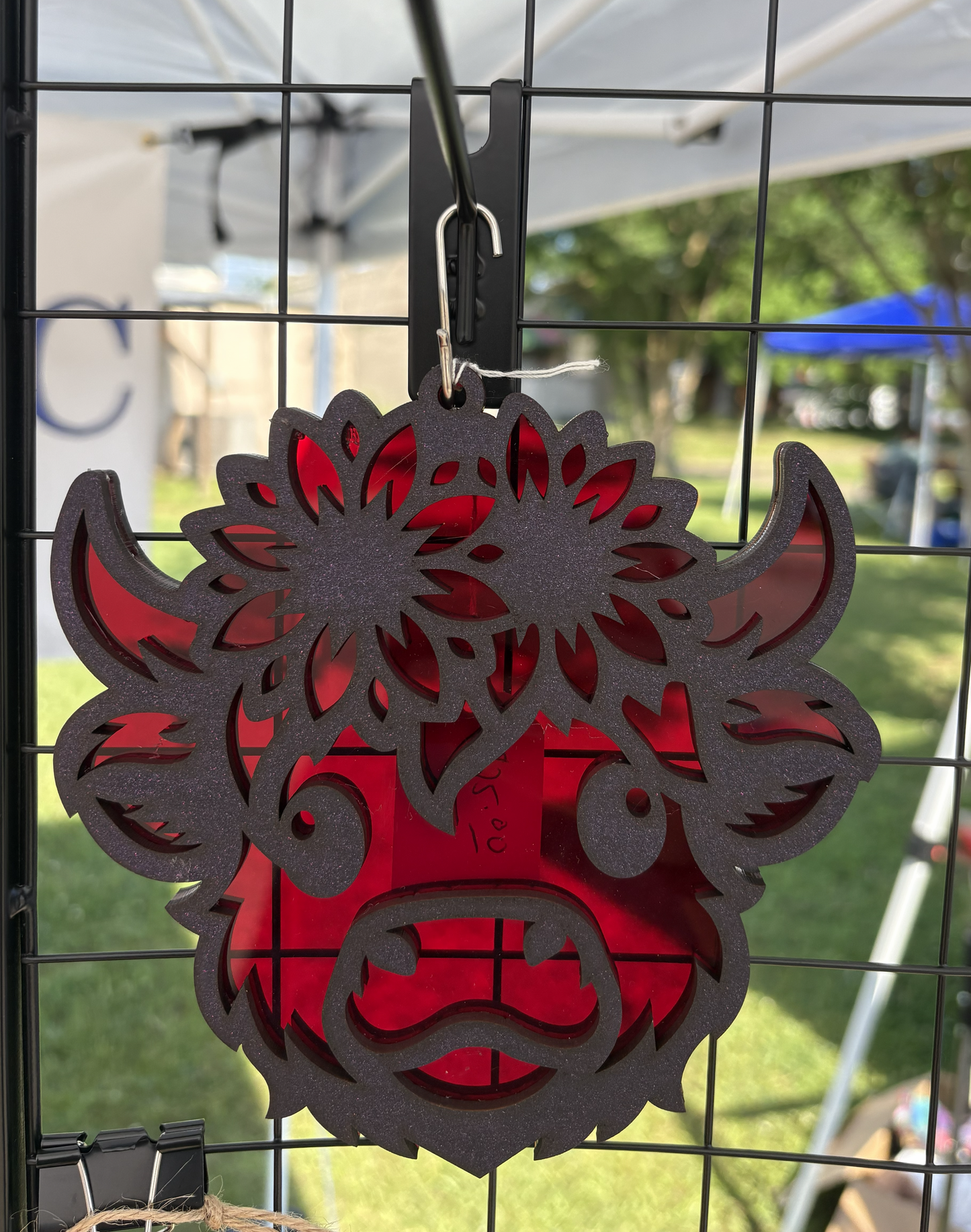 Decorative metal pig head ornament with red and black colors on a wire rack.